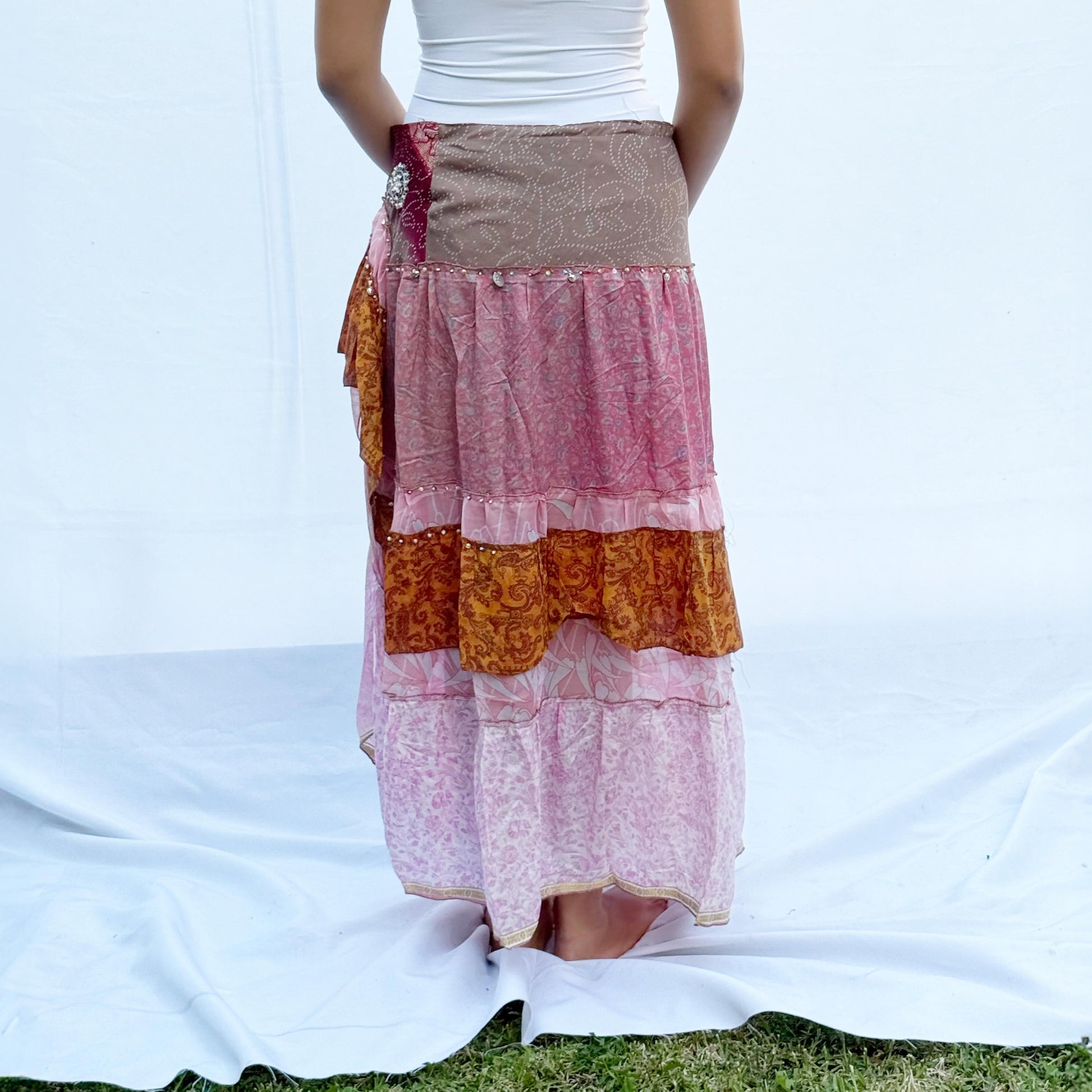 A patchwork skirt made from vintage saris, featuring soft pink, brown, and gold tones with intricate patterns. It includes an adjustable drawstring for a comfortable fit.