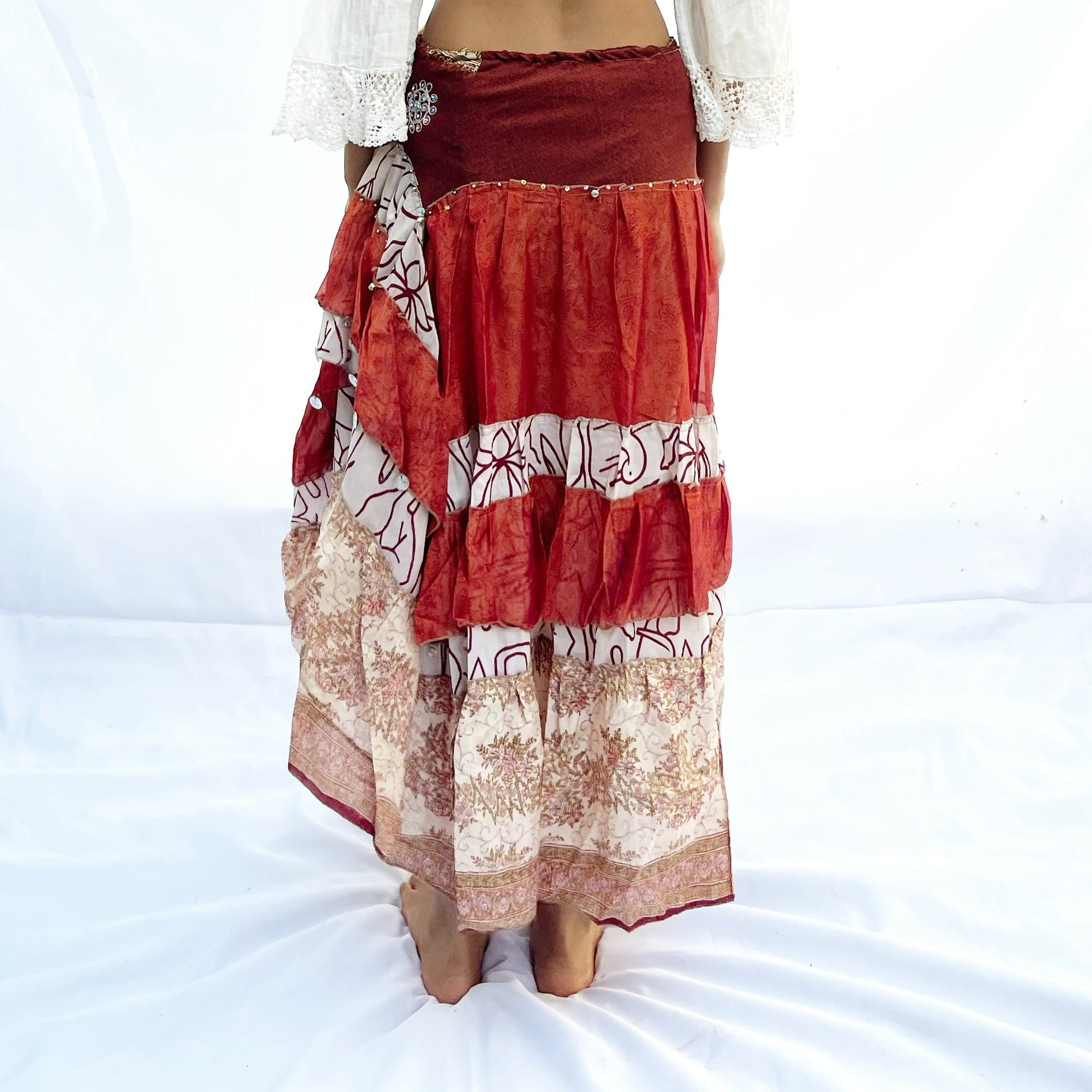 A vintage drawstring skirt crafted from sari fabric, featuring rich shades of red, black, and beige with intricate patterns. The design is flowy and adjustable for a comfortable fit.