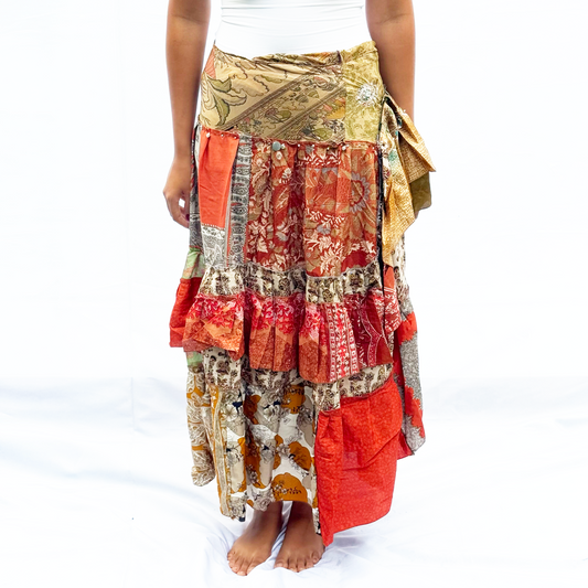 A vibrant patchwork skirt made from vintage saris, featuring warm earthy tones of red, orange, and beige. It has an adjustable drawstring for a customisable fit.