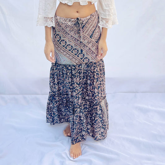 A drawstring skirt made from vintage sari fabric, featuring intricate patterns in shades of black, beige, and blue with floral designs. The adjustable fit adds elegance and comfort.