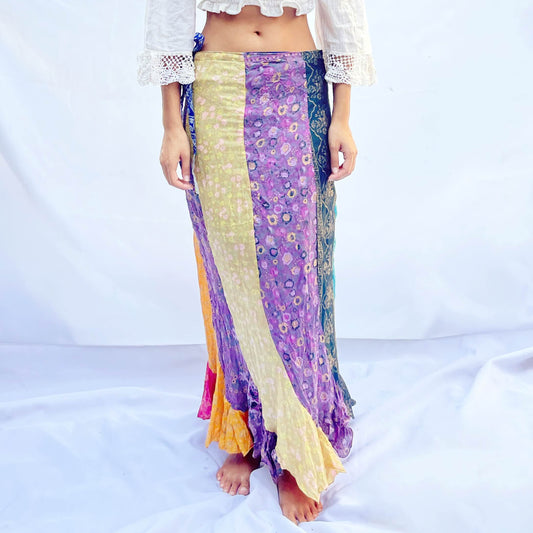 A reversible wrap skirt made from vintage sari fabric, featuring flowing panels in vibrant shades of purple, yellow, and green. The design offers versatility and elegance.