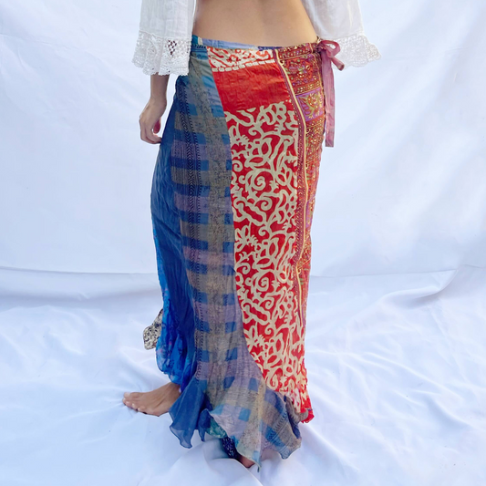 A reversible wrap skirt crafted from vintage sari fabric, featuring a mix of blue, beige, and multicoloured patterns. The flowing design offers versatility and style.