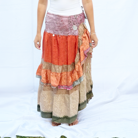 A vibrant patchwork skirt made from vintage saris, featuring shades of orange, pink, beige, and green with intricate patterns. The skirt includes an adjustable drawstring for a customisable fit.