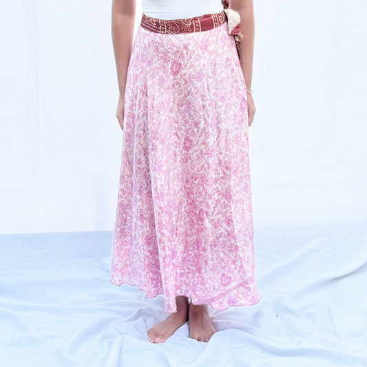 A unique skirt crafted from vintage rayon sari fabric, featuring a delicate pink floral pattern with a traditional maroon border. This flowing wrap design offers an elegant, adjustable fit and is reversible.