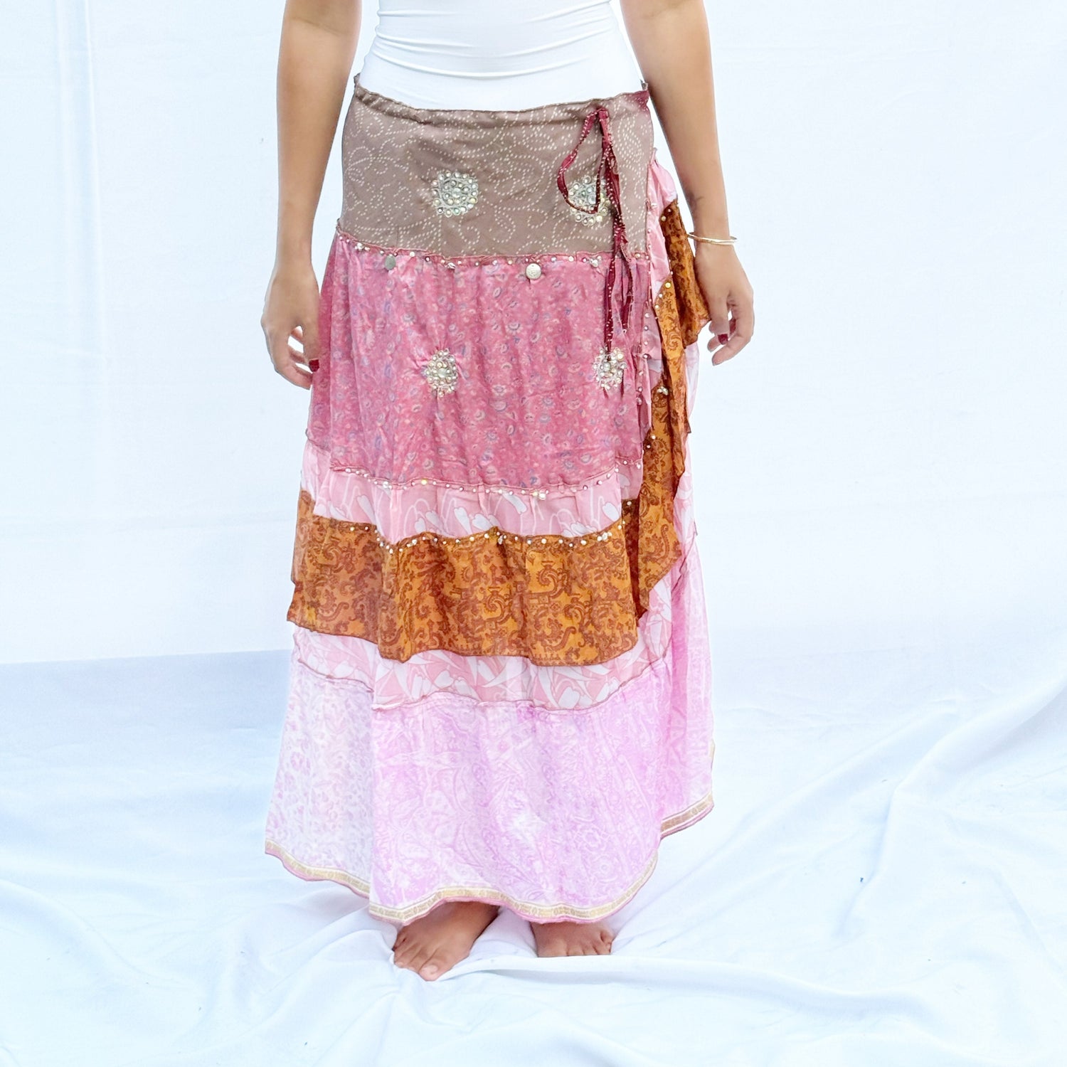 A patchwork skirt made from vintage saris, featuring soft pink, brown, and gold tones with intricate patterns. It includes an adjustable drawstring for a comfortable fit.