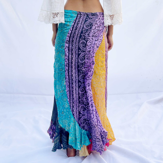 A reversible wrap skirt made from vintage sari fabric, featuring flowing panels in vibrant shades of purple, yellow, and green. The design offers versatility and elegance.